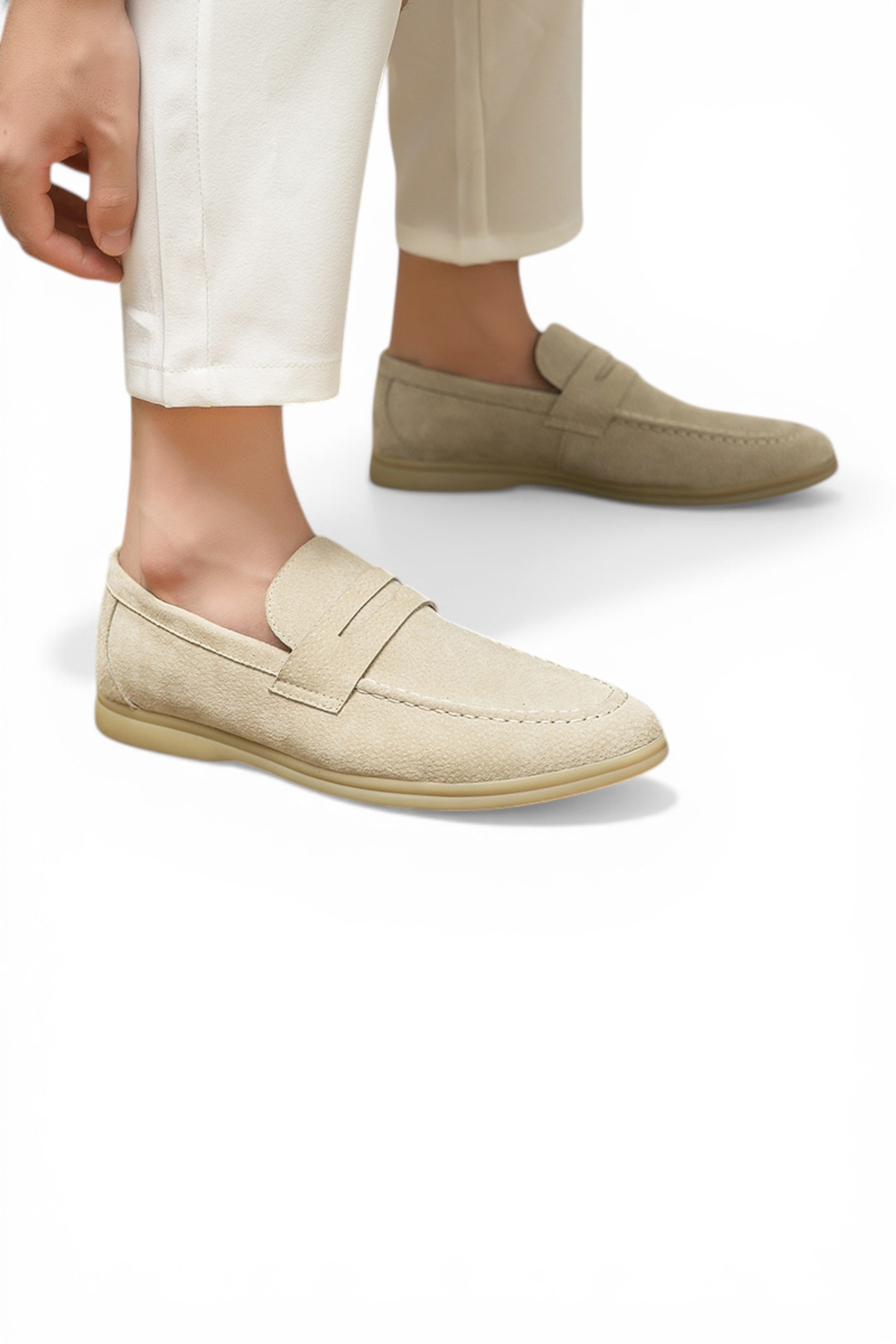 Beige loafers worn with white pants on a light background