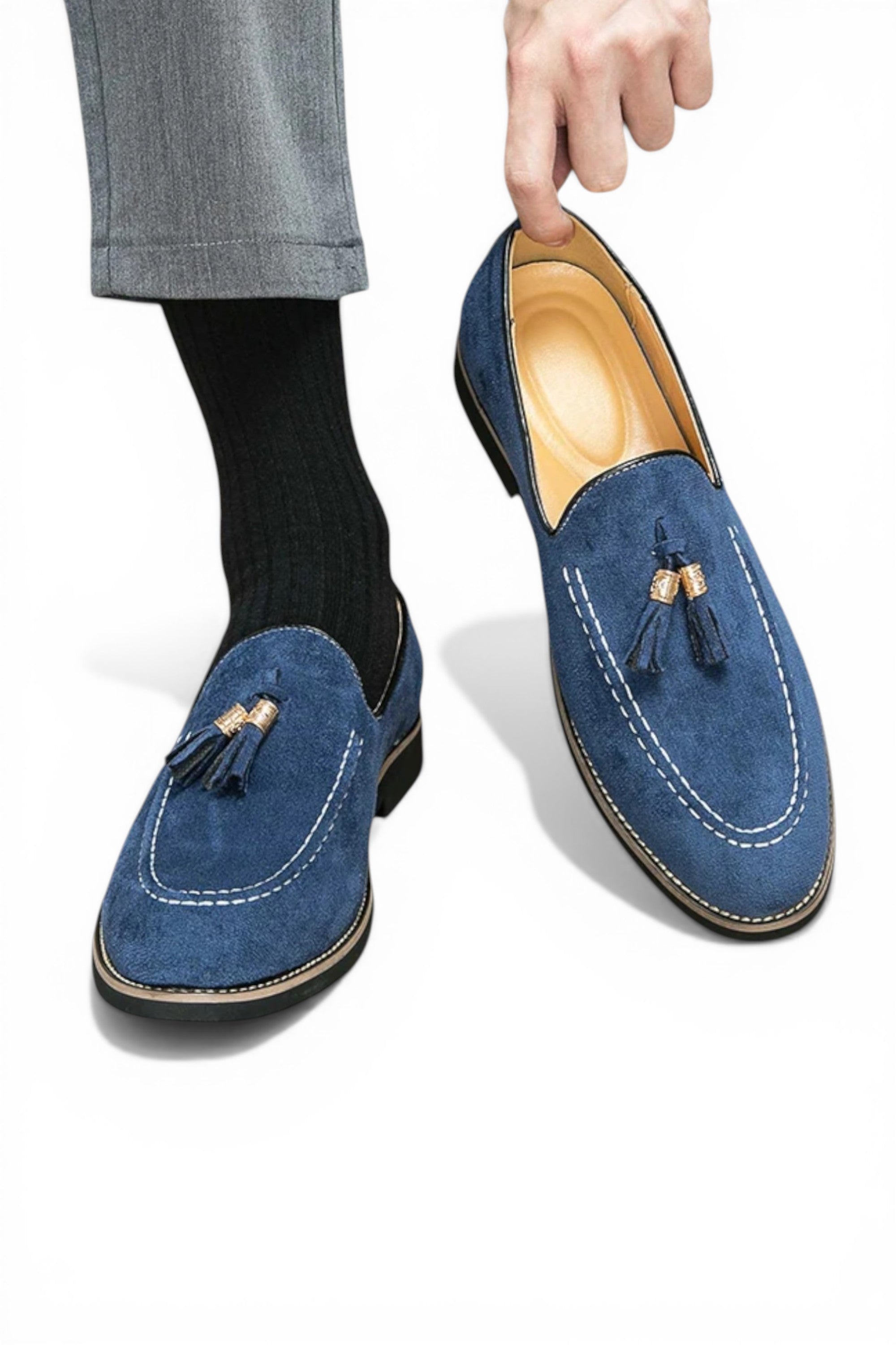Blue suede loafers with tassels held by a hand on a white background