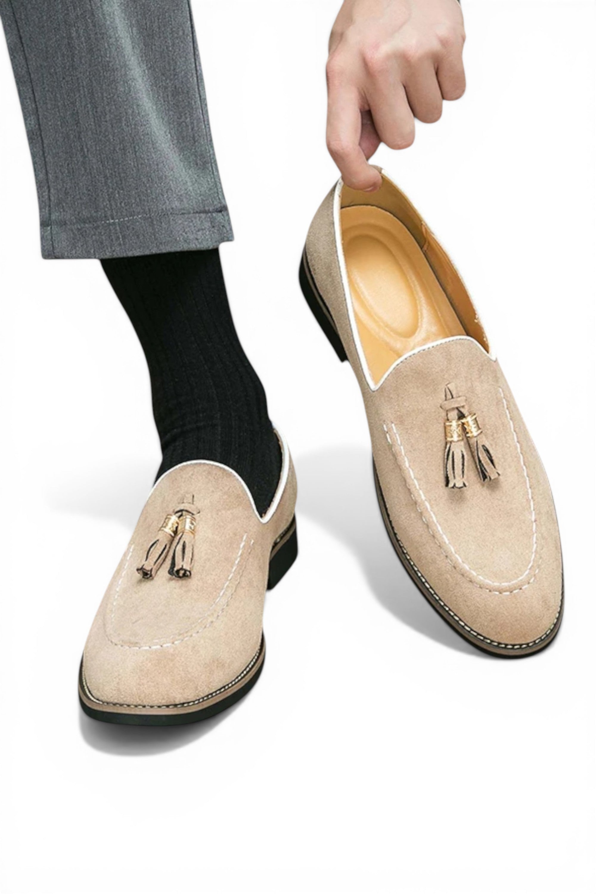 Beige loafers with tassels worn by a person on a white background