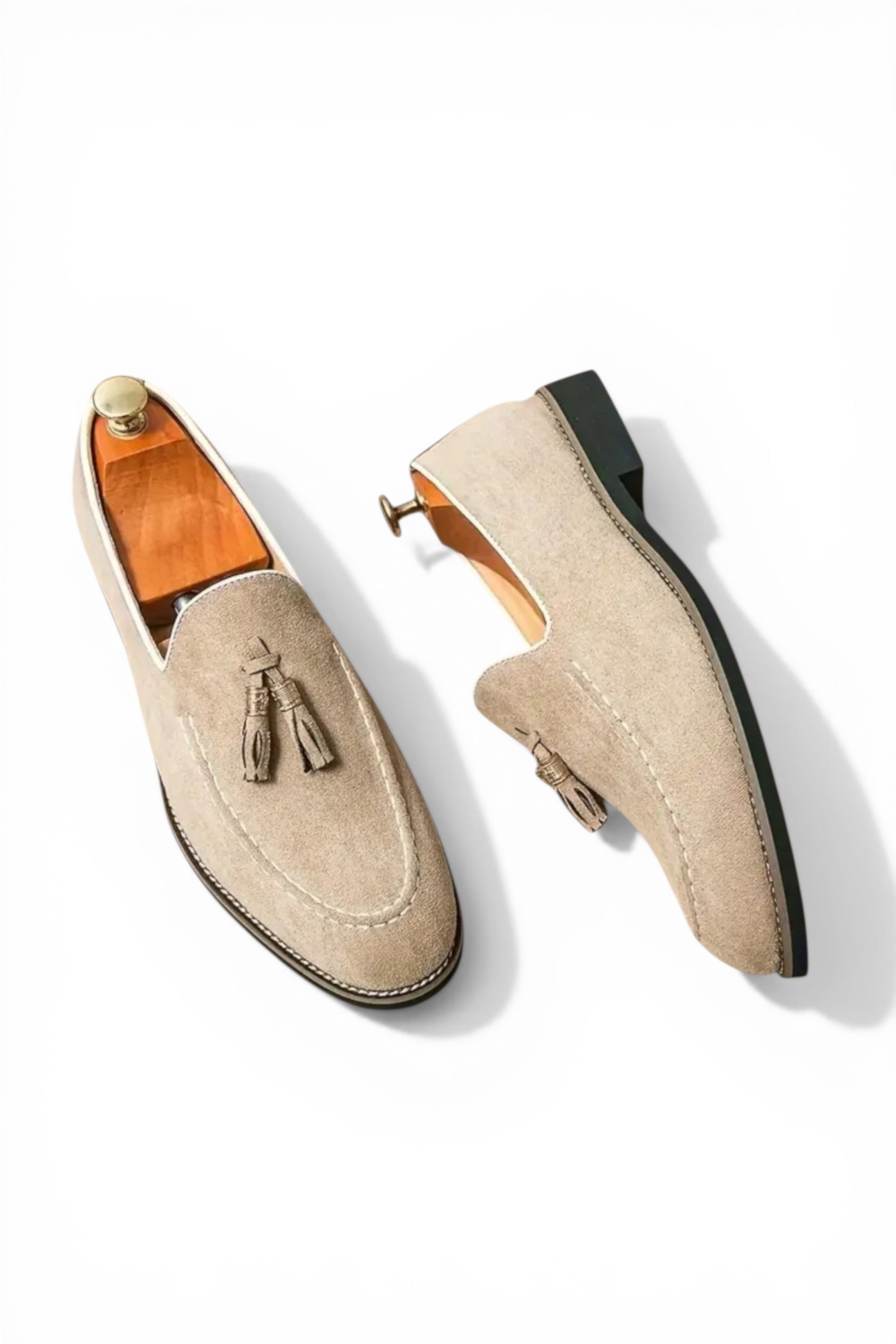 Pair of beige loafers with tassels on a white background