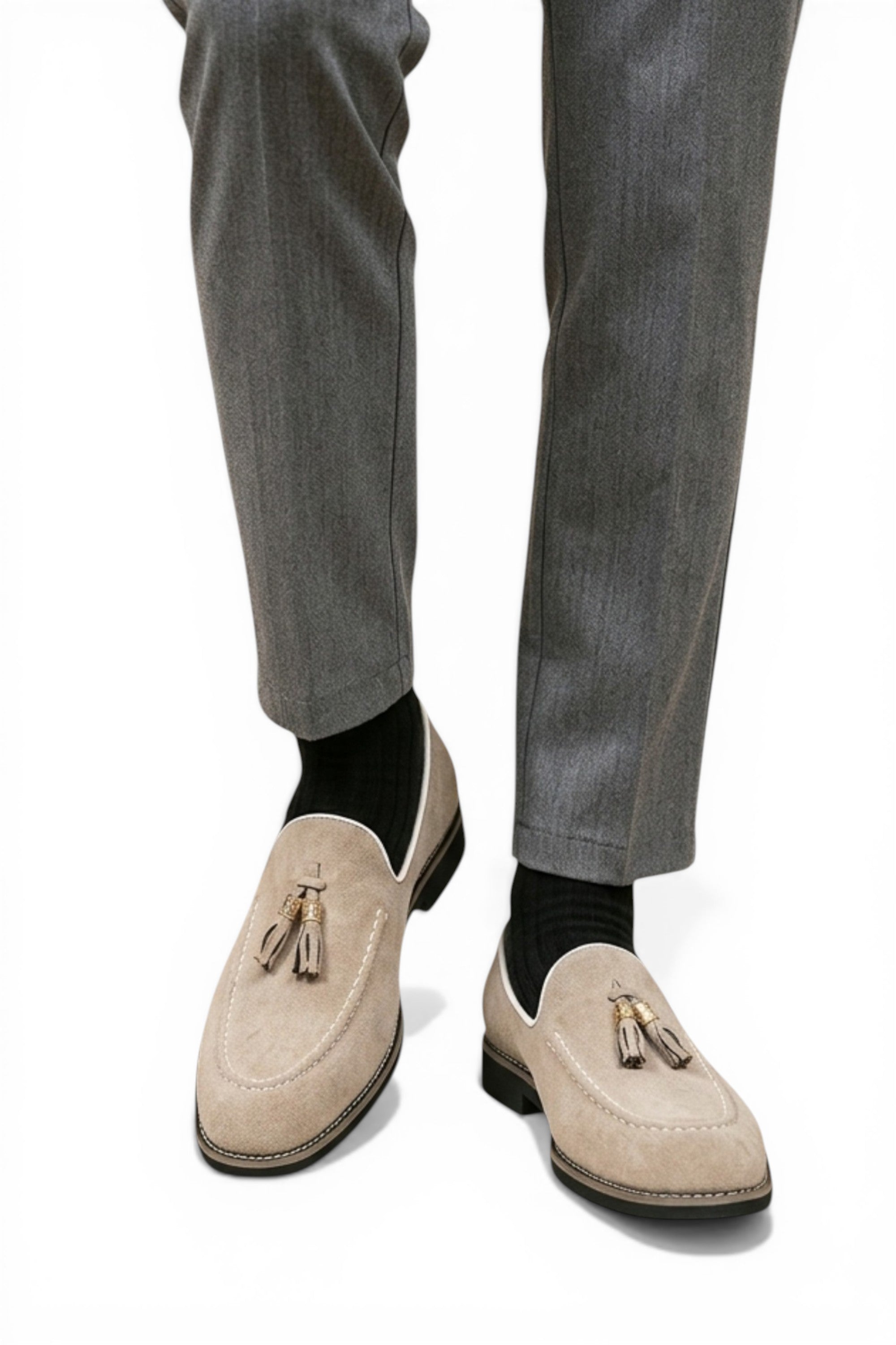 Beige loafers with tassels worn with gray pants on a white background