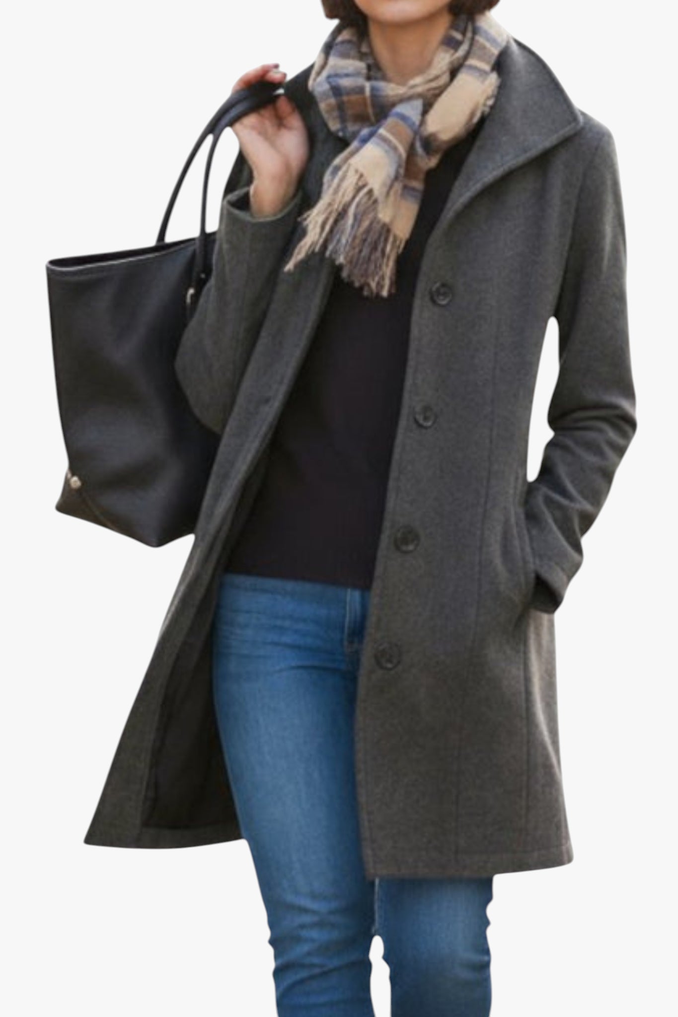 Person wearing a gray coat, black sweater, blue jeans, and holding a black tote bag with a plaid scarf.