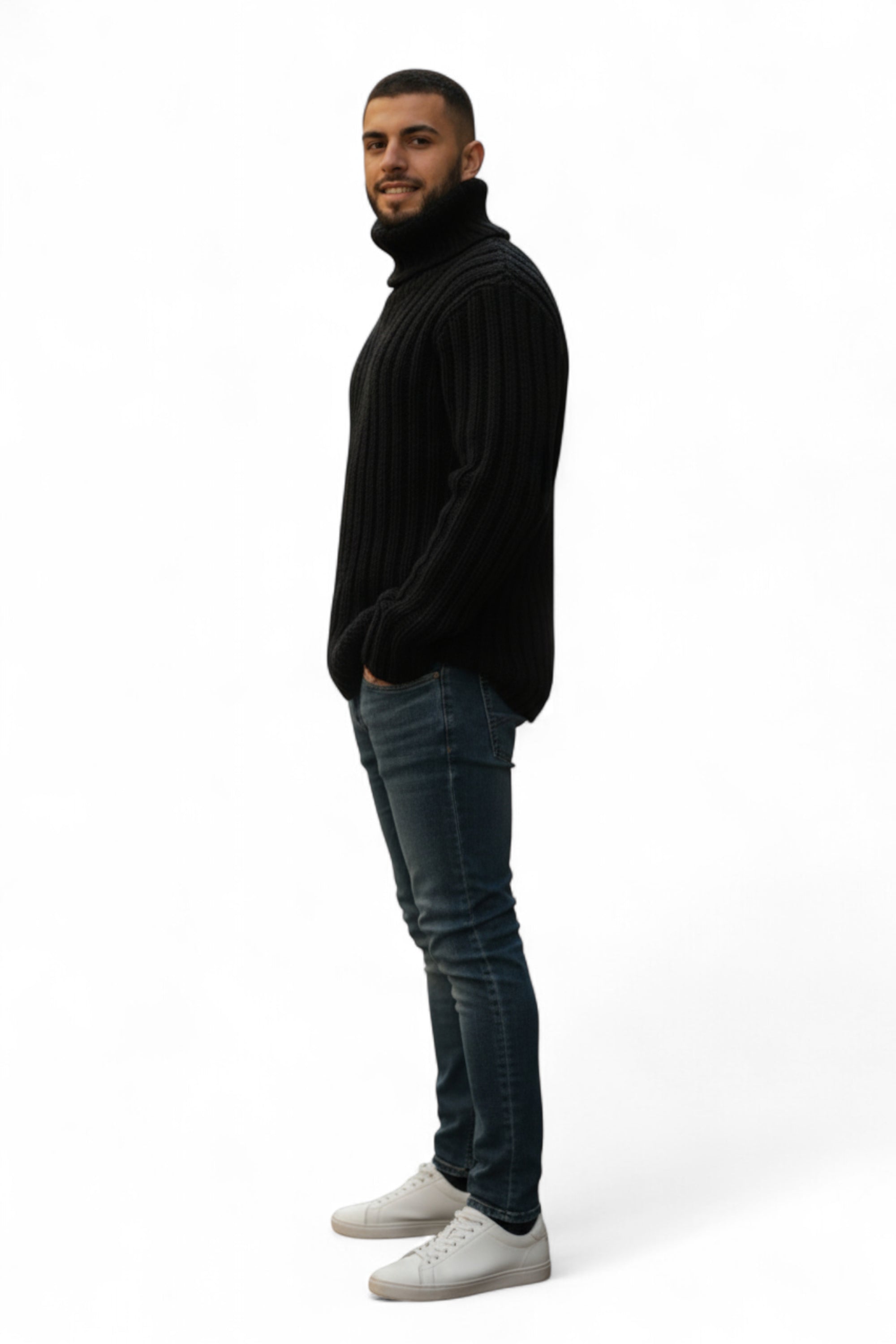 Man wearing a black turtleneck sweater, blue jeans, and white sneakers on a white background