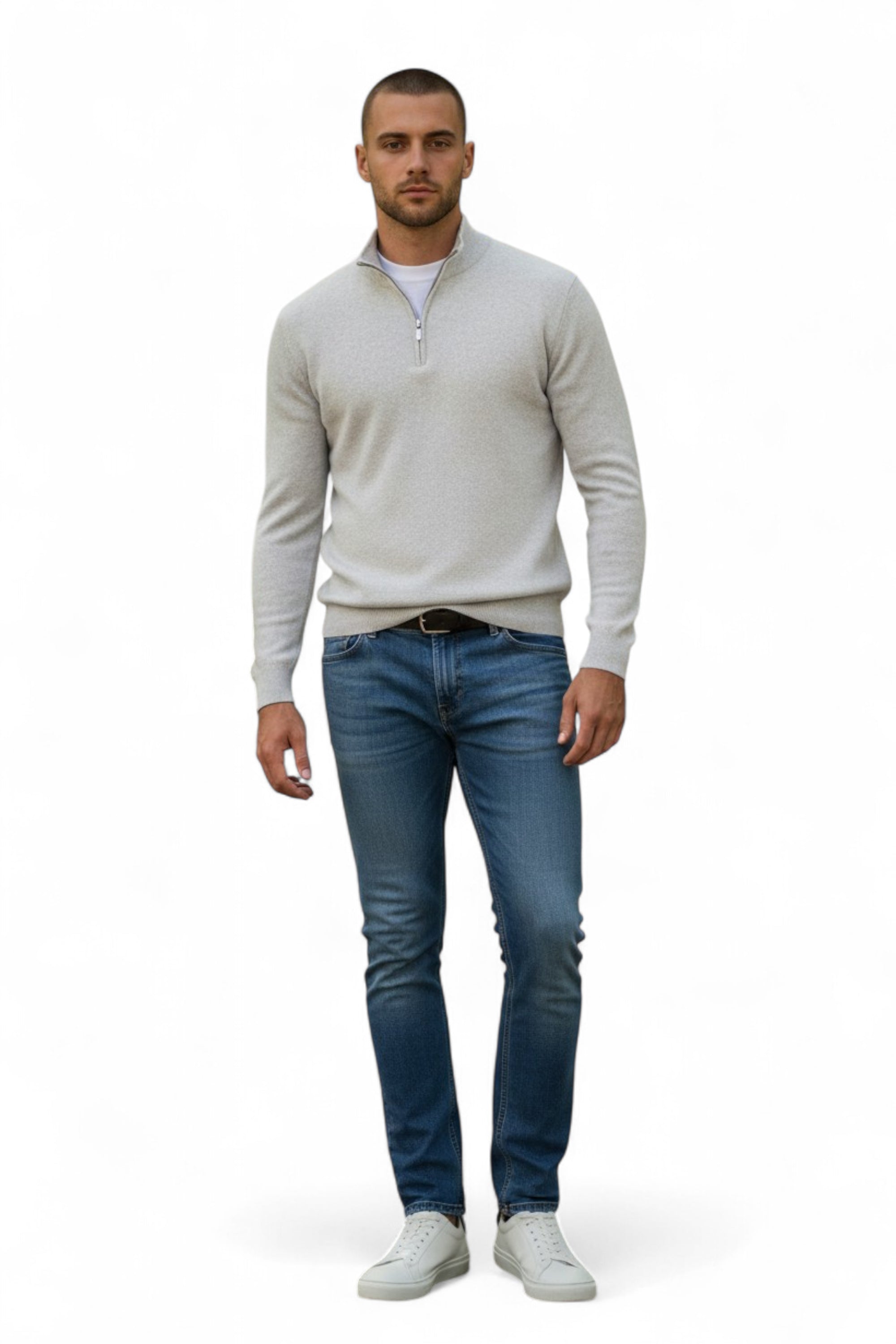 Man wearing a light gray sweater, blue jeans, and white shoes on a white background