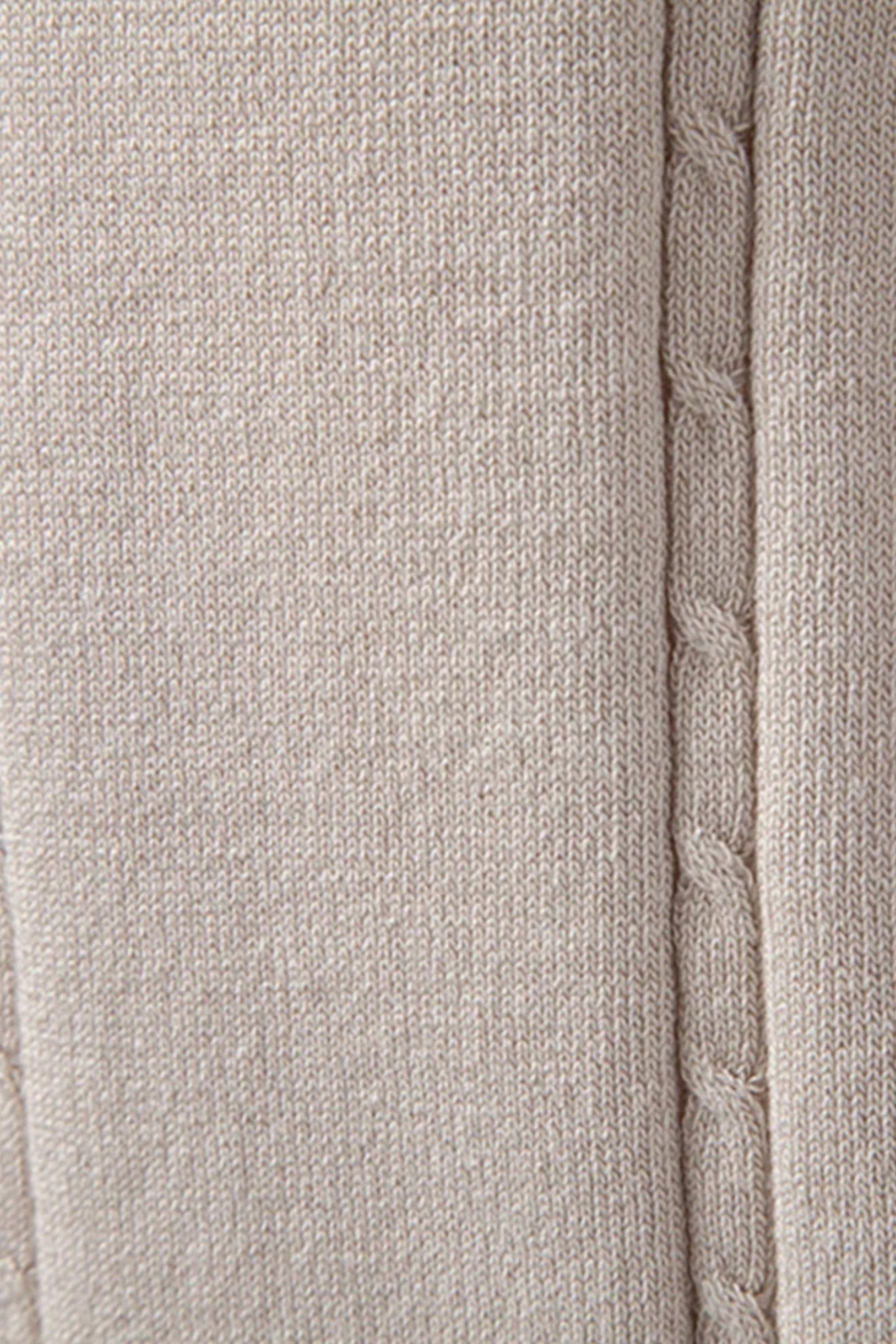 Close-up of a textured fabric with a cable knit pattern on a neutral background