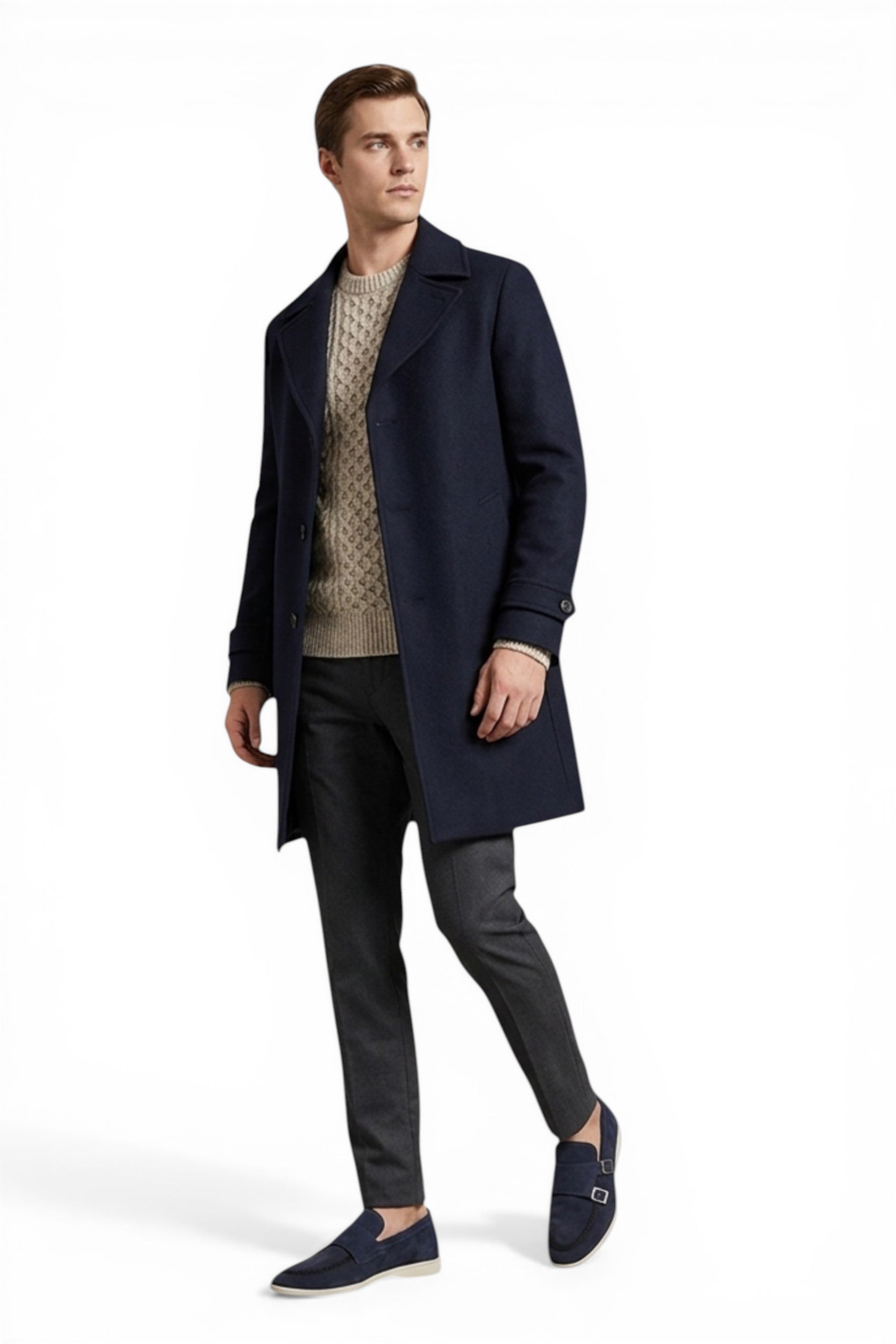 Man wearing a navy coat over a patterned sweater with dark pants on a white background