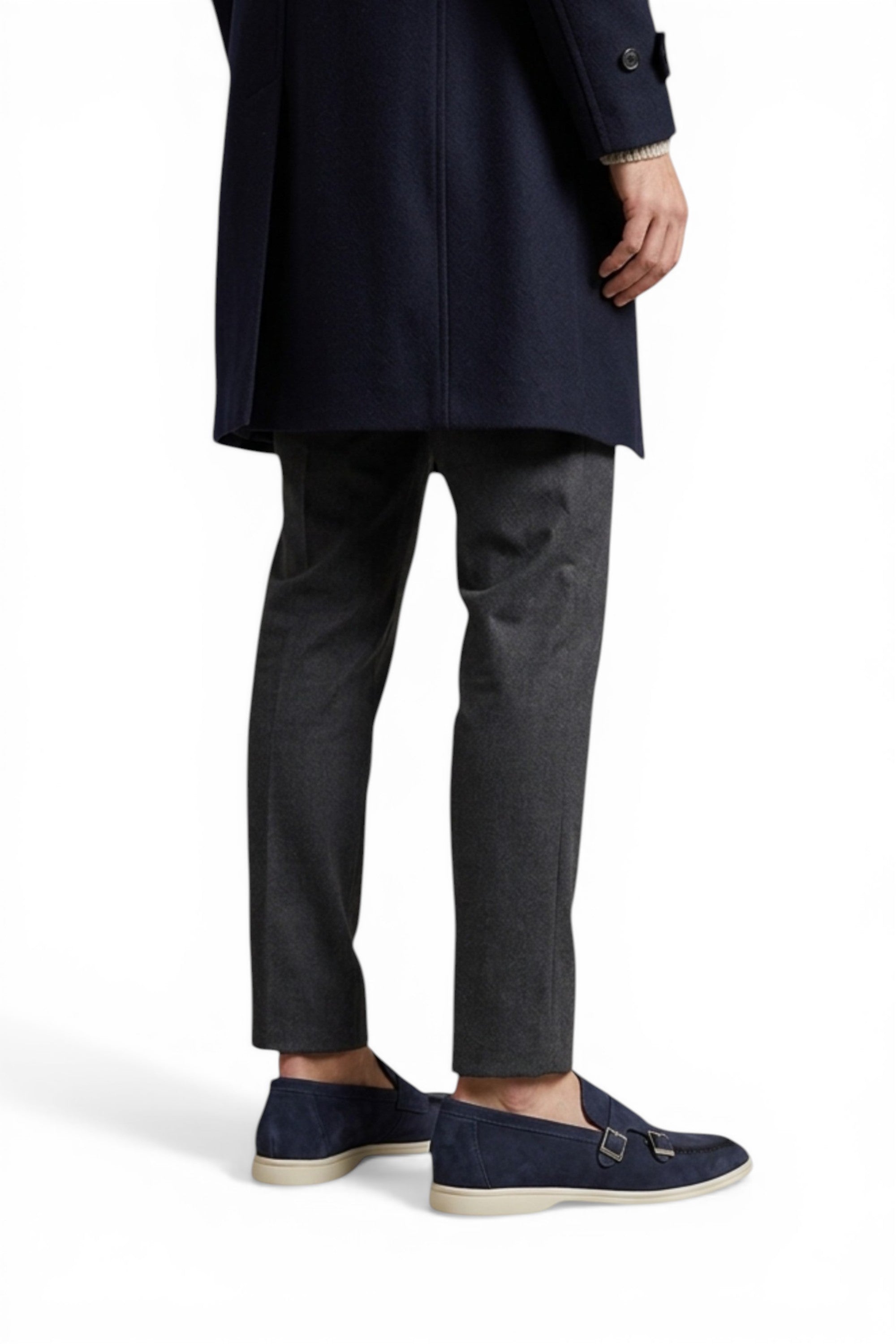 Person wearing a navy coat, gray pants, and navy shoes on a white background