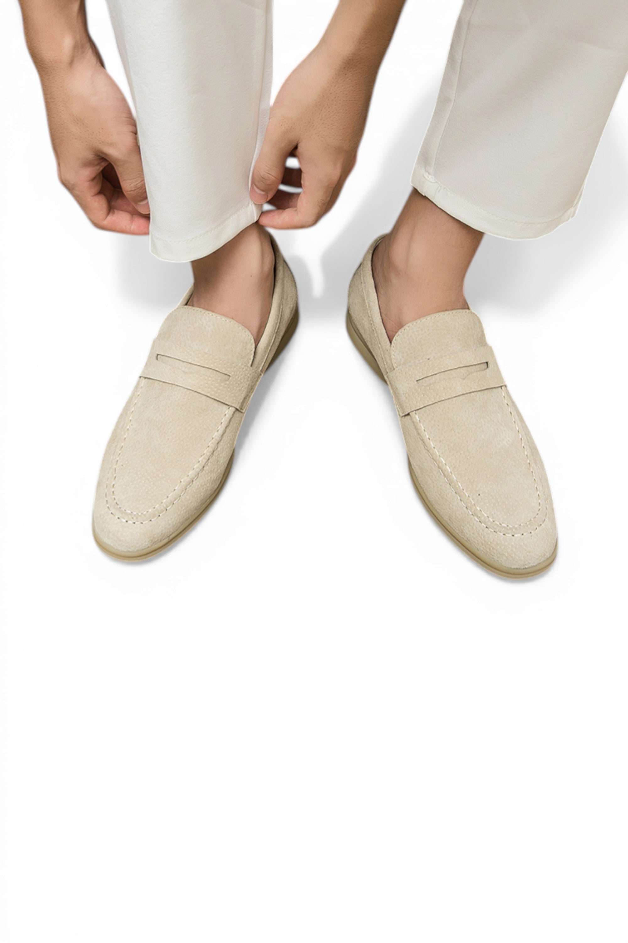 Beige loafers worn with white pants on a white background
