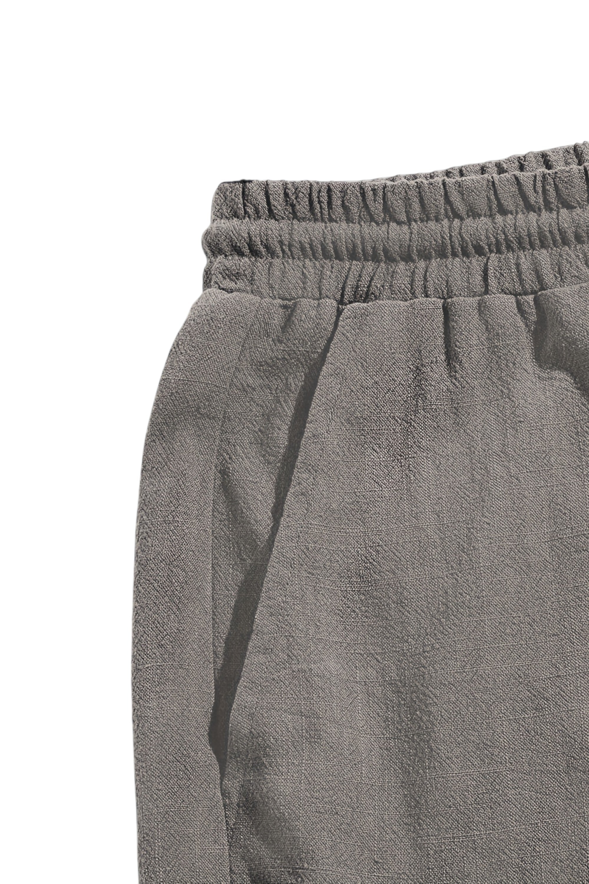 Close-up of gray sweatpants with an elastic waistband on a white background