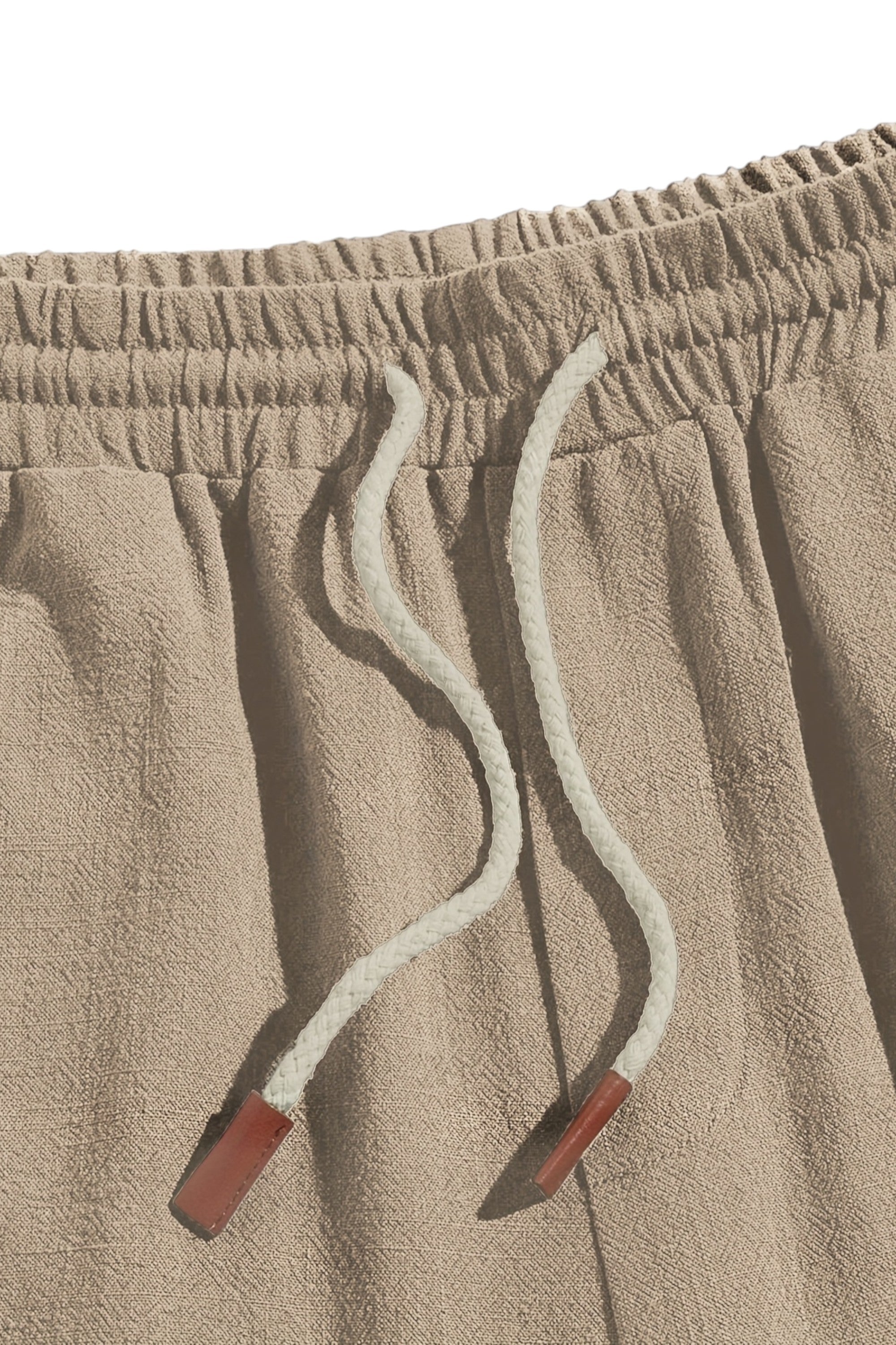 Close-up of beige sweatpants with drawstring and red buttons on a light gray background