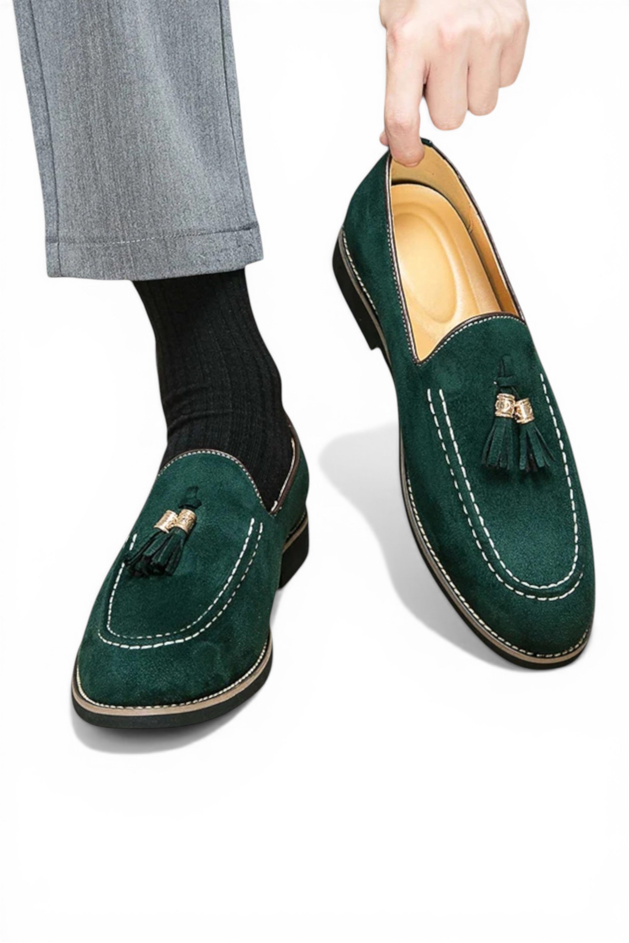 Green loafers with tassels worn by a person on a white background