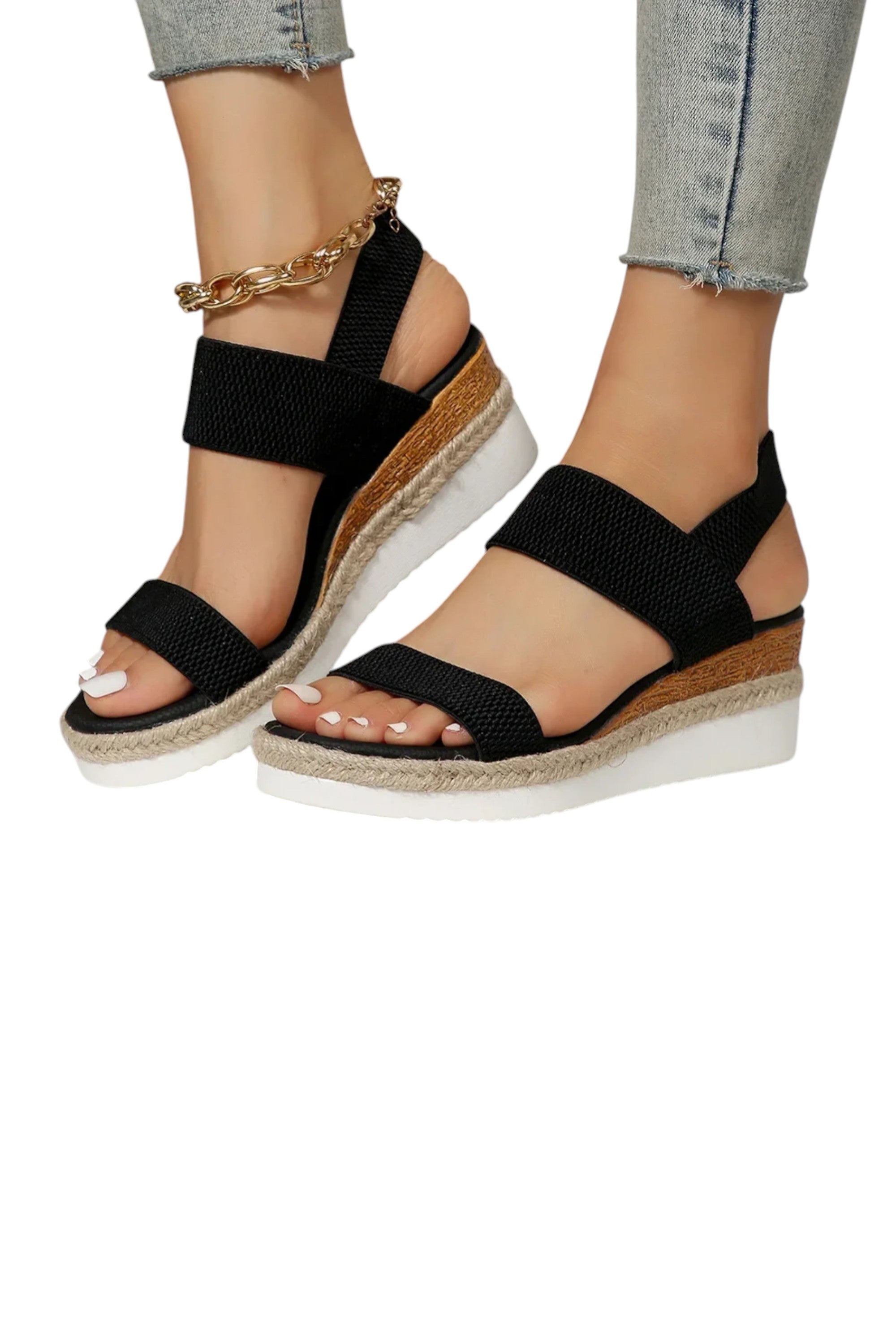 Black wedge sandals with cork sole worn by a person on a white background