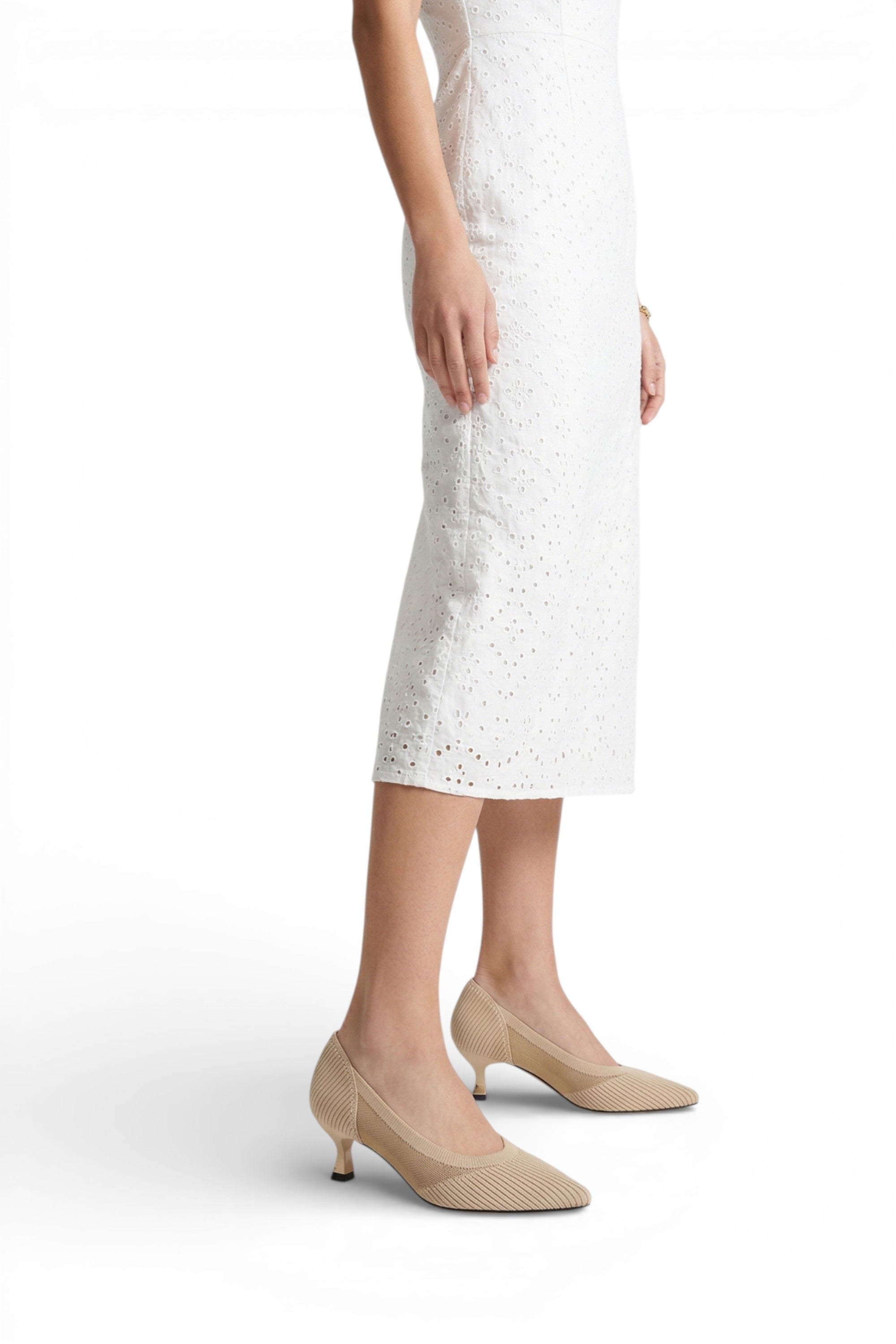 Person wearing a white lace dress and beige shoes on a white background