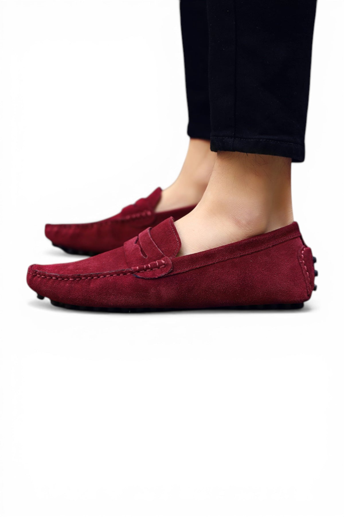 Burgundy loafers worn with black pants on a white background